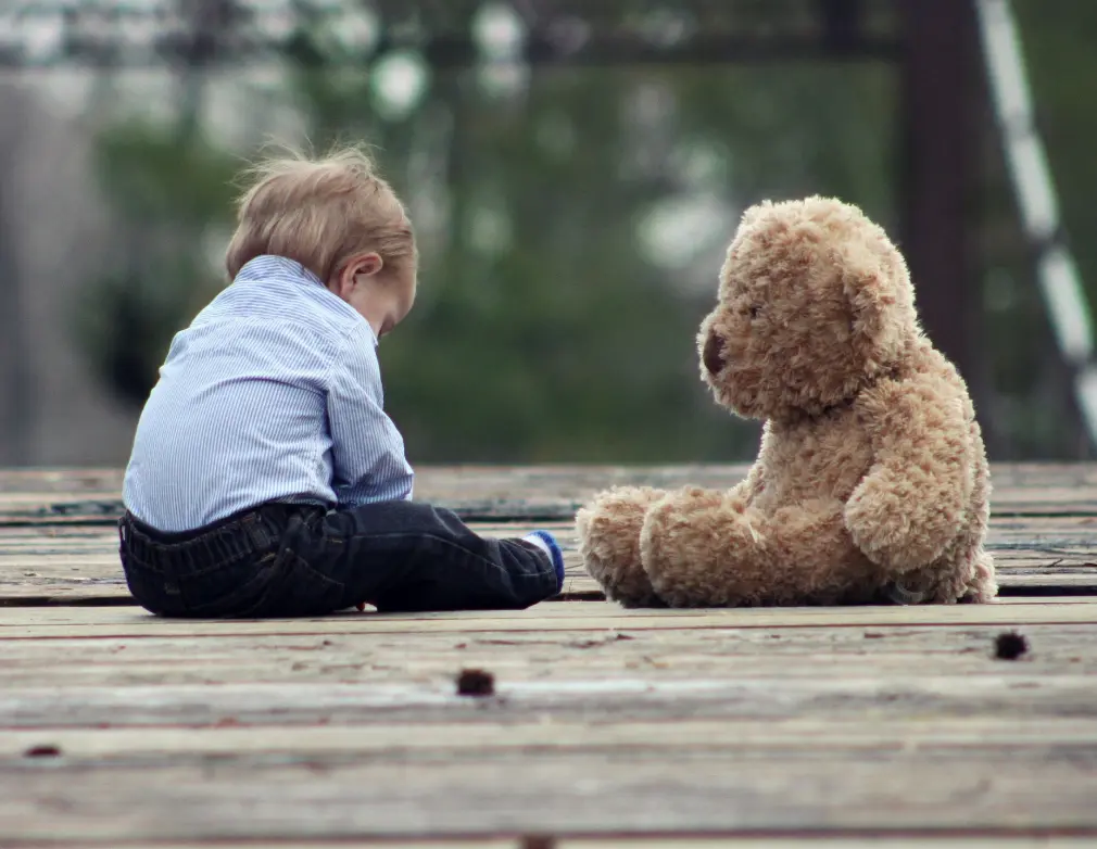 A boy play with a teddy bear